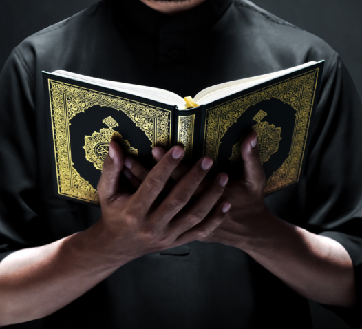 En person håller en bok med gulddetaljer i händerna.